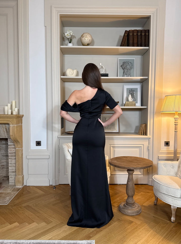 Robe de soirée noire chic au col asymétrique, sans manches et sans fente. Une robe élégante et moderne pour vos soirées raffinées.