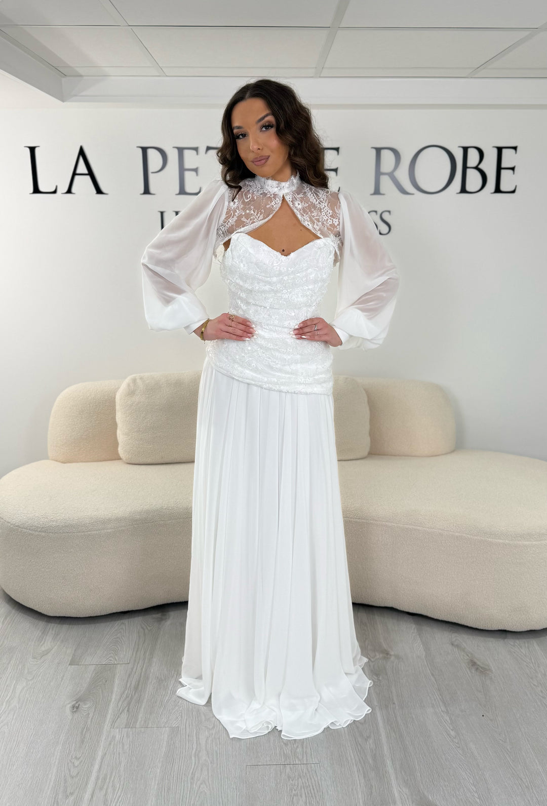 Robe de mariée blanche longue avec décolleté bustier sous col montant en dentelle et boléro amovible. Élégante, sans fente, idéale mariage 2026.