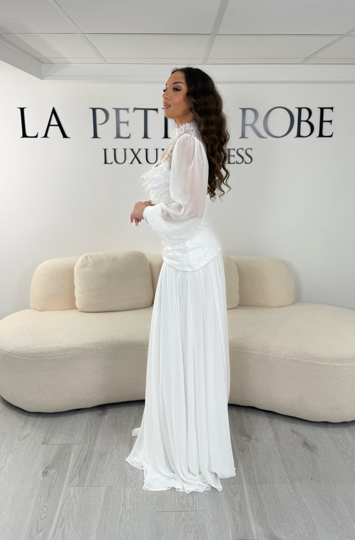 Robe de mariée blanche longue avec décolleté bustier sous col montant en dentelle et boléro amovible. Élégante, sans fente, idéale mariage 2026.