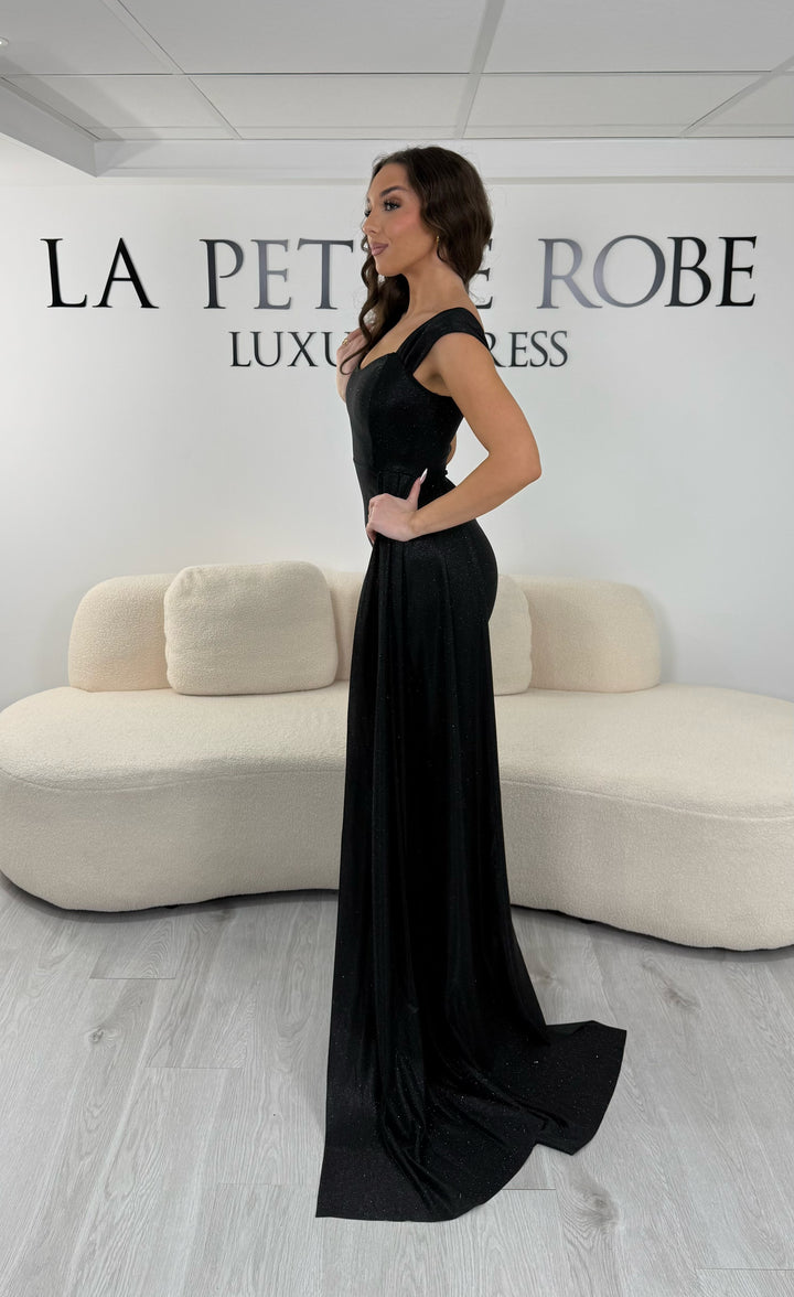 Robe de soirée noire longue avec traîne élégante, décolleté cœur et coupe ajustée. Sans fente, parfaite pour gala ou soirée chic 2026.