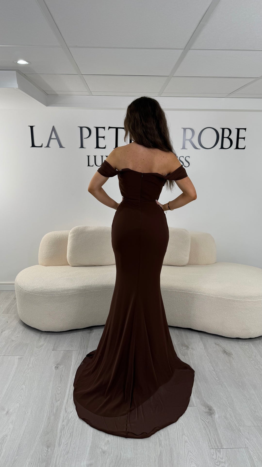 Robe de soirée marron élégante avec drapé et épaules dénudées. Coupe longue sans fente, parfaite pour une soirée chic.
