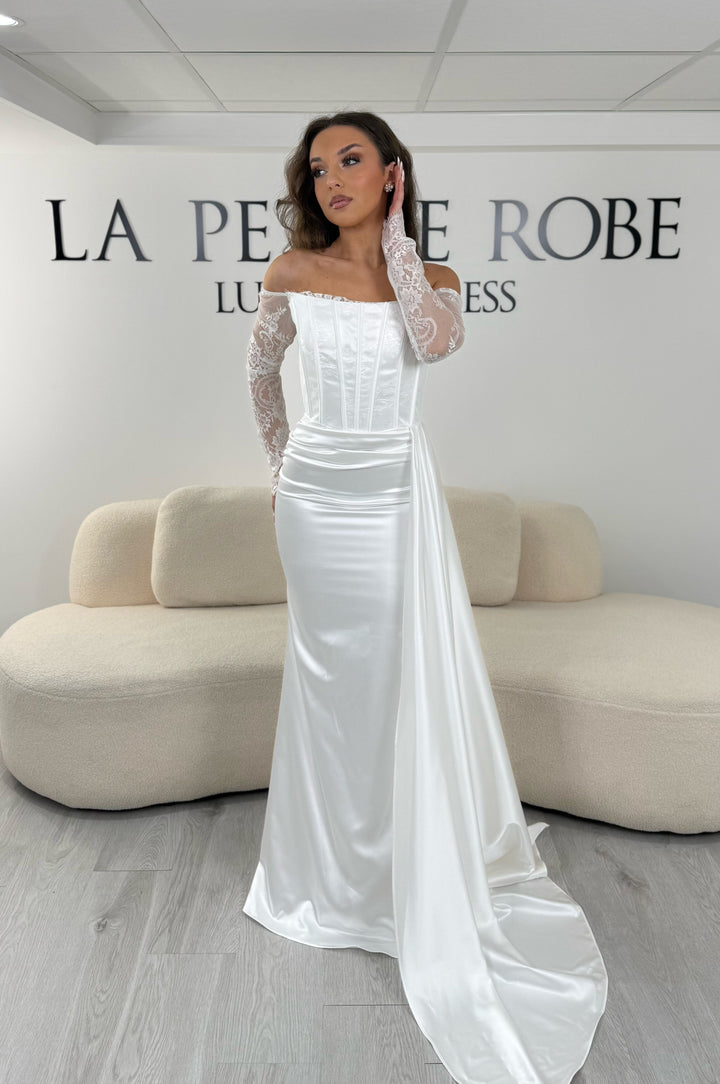 Robe de mariée blanche élégante avec dentelle et traîne sur le côté. Coupe longue sans fente, idéale pour une cérémonie chic.