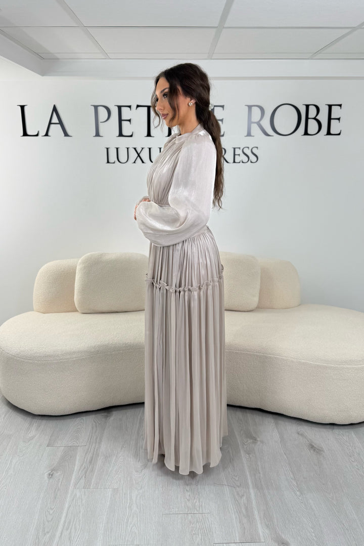 Robe de soirée modeste beige élégante avec manches longues et plissé. Coupe longue sans fente, parfaite pour une tenue chic.