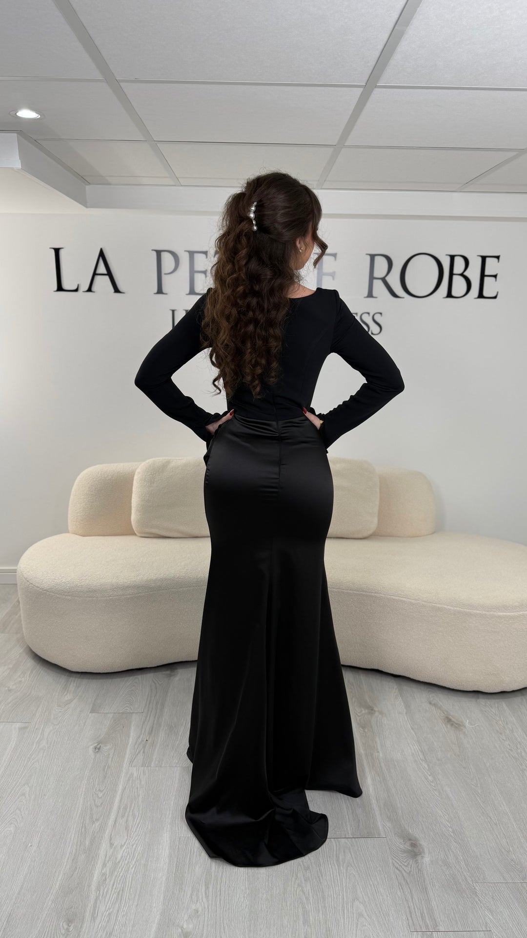 Robe de soirée noire élégante avec col carré, manches longues et coupe ajustée sans fente. Idéale pour un look chic et raffiné.