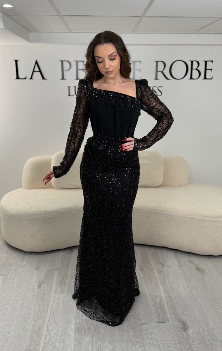 Robe de soirée noire élégante sans fente, avec manches longues et détails scintillants. Parfaite pour un look chic et sophistiqué.