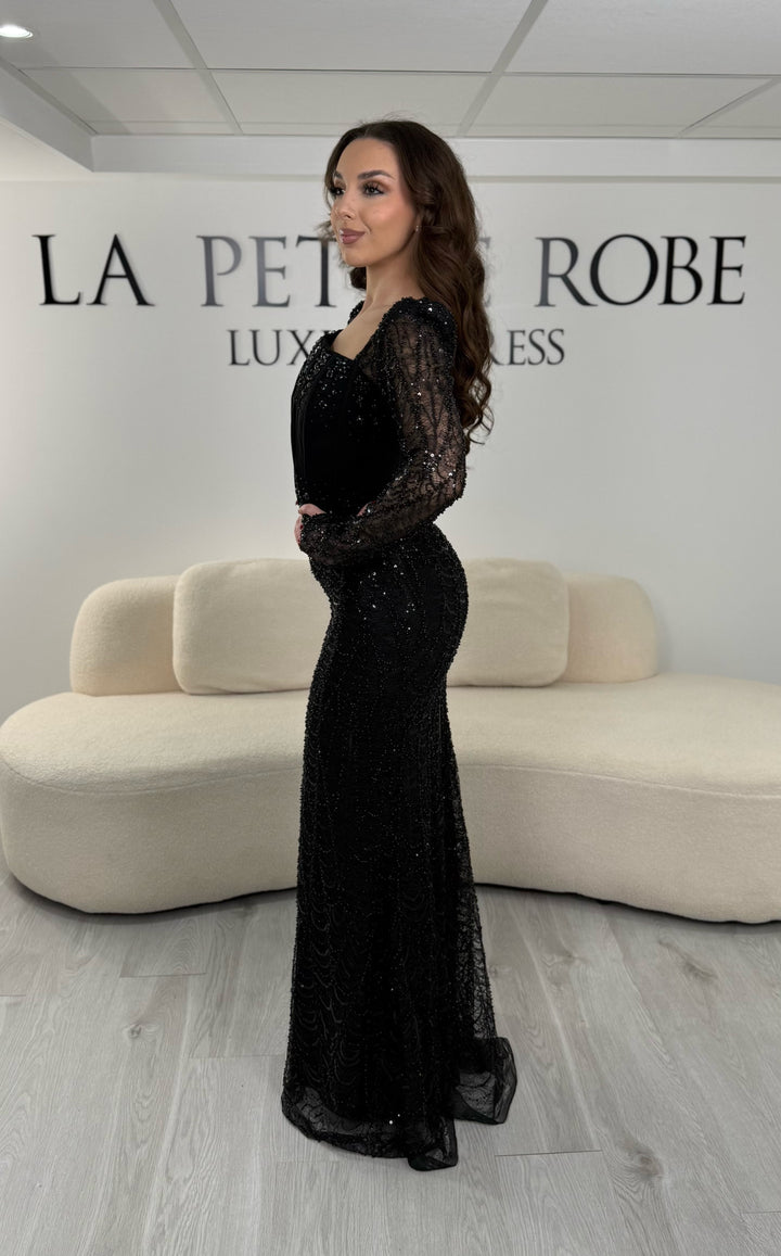 Robe de soirée noire élégante sans fente, avec manches longues et détails scintillants. Parfaite pour un look chic et sophistiqué.