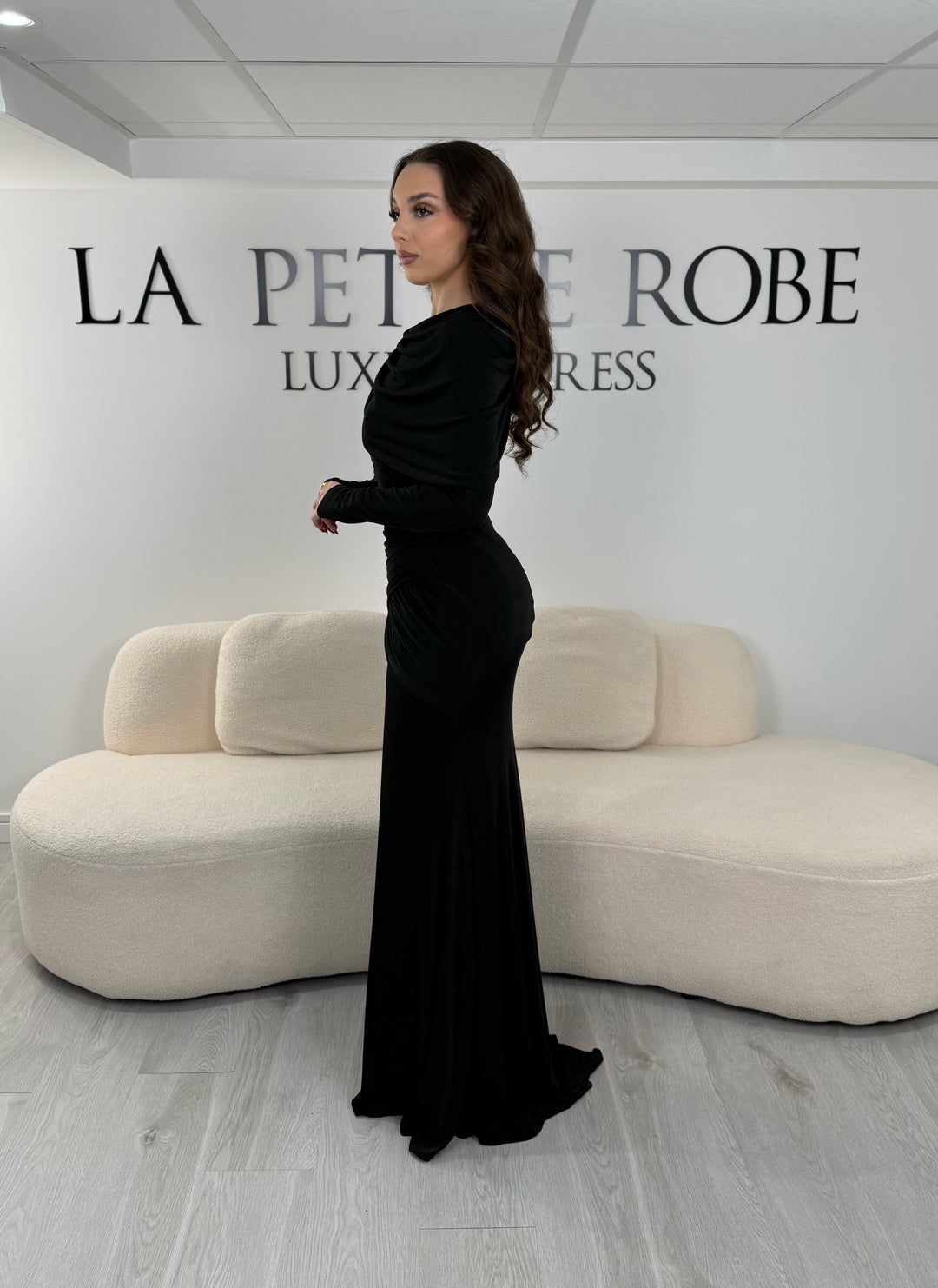 Robe de soirée noire en jersey stretch élégante, sans fente, avec manches longues et coupe fluide. Idéale pour un look chic et confortable.