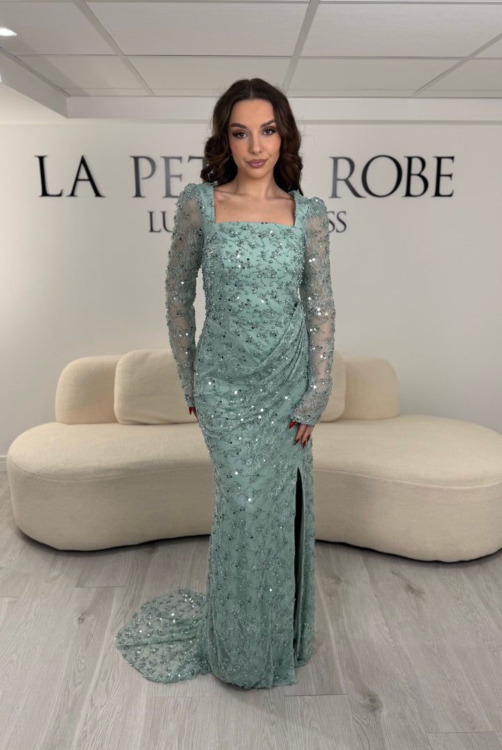 Robe de soirée vert d’eau élégante avec col carré, manches longues et fente glamour. Idéale pour un look chic, lumineux et raffiné.