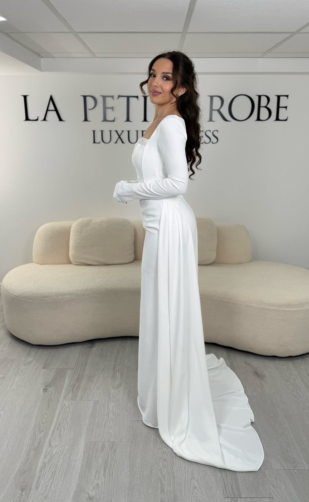 Robe de mariée blanche élégante avec col carré, manches longues et traîne amovible sans fente. Idéale pour un look chic et raffiné.