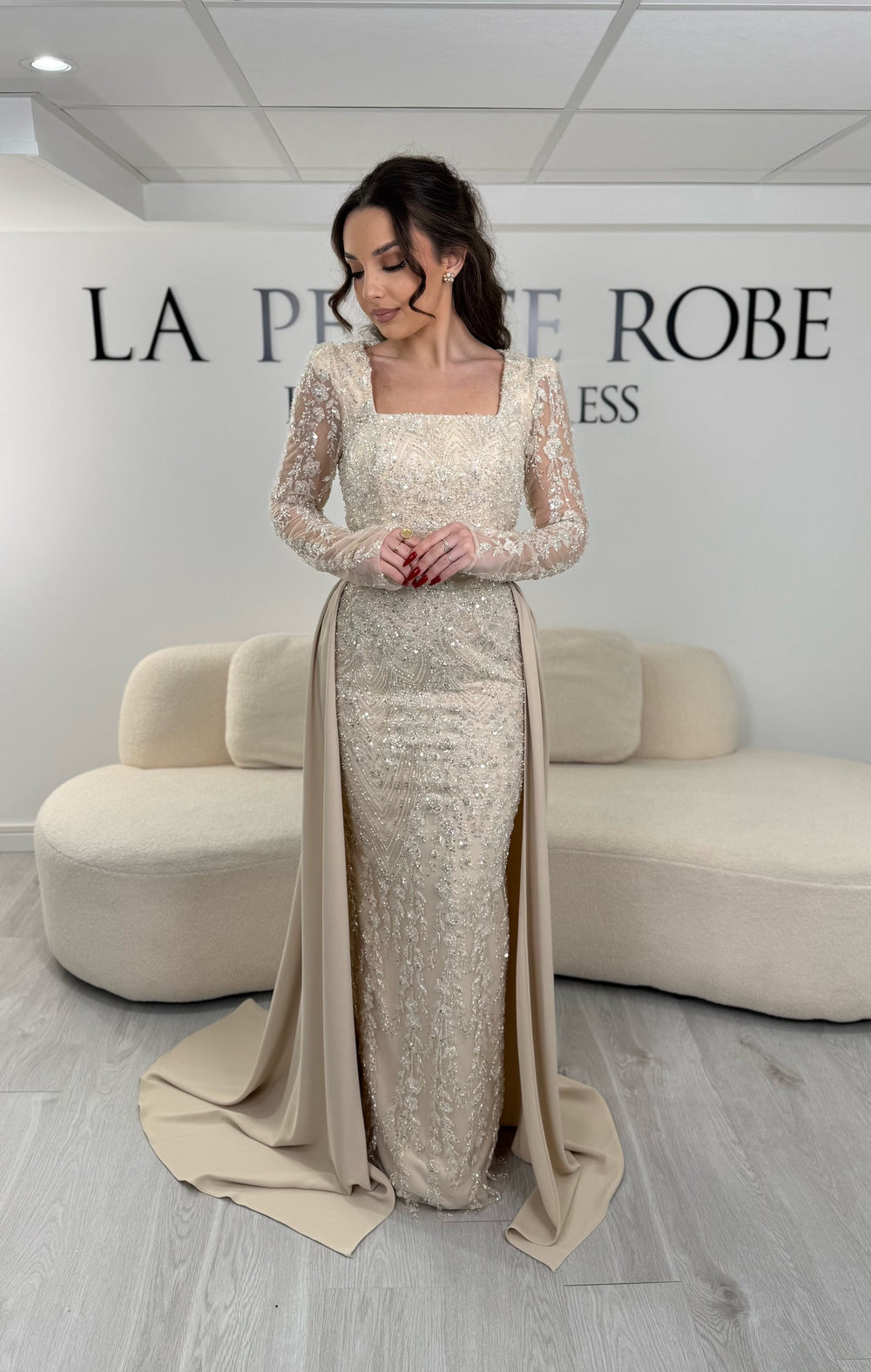 Robe de soirée beige élégante avec col carré, manches longues et traîne amovible sans fente. Idéale pour un look chic et raffiné.