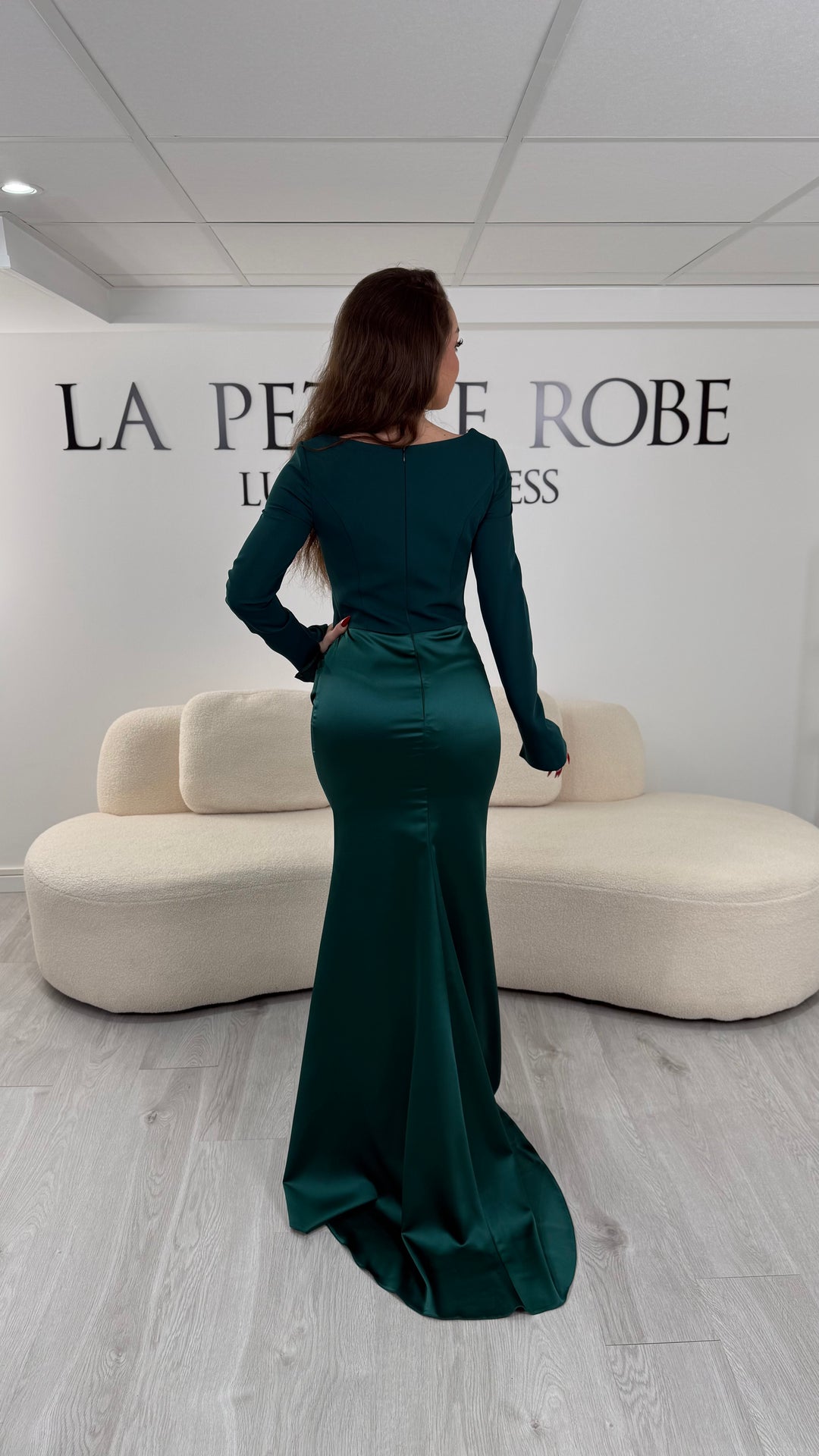 Robe de soirée vert émeraude avec col carré, manches longues et corset structuré. Coupe ajustée sans fente avec drapé élégant, idéale pour une allure chic.