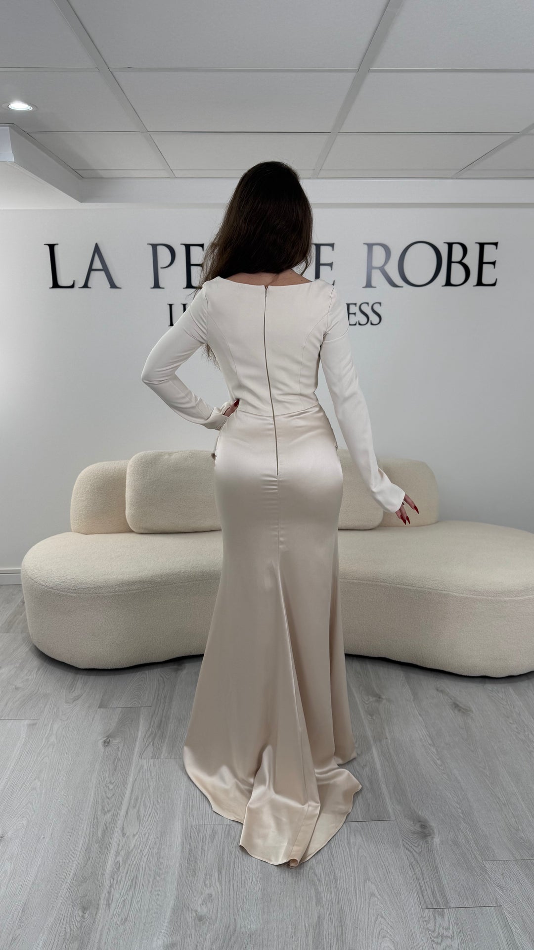 Robe de soirée beige avec col carré, manches longues et corset structuré. Coupe ajustée sans fente avec drapé élégant, idéale pour une allure chic.