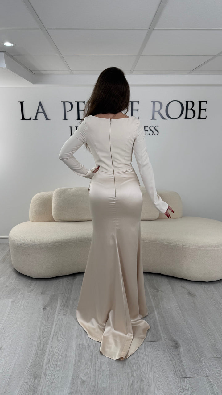 Robe de soirée beige avec col carré, manches longues et corset structuré. Coupe ajustée sans fente avec drapé élégant, idéale pour une allure chic.