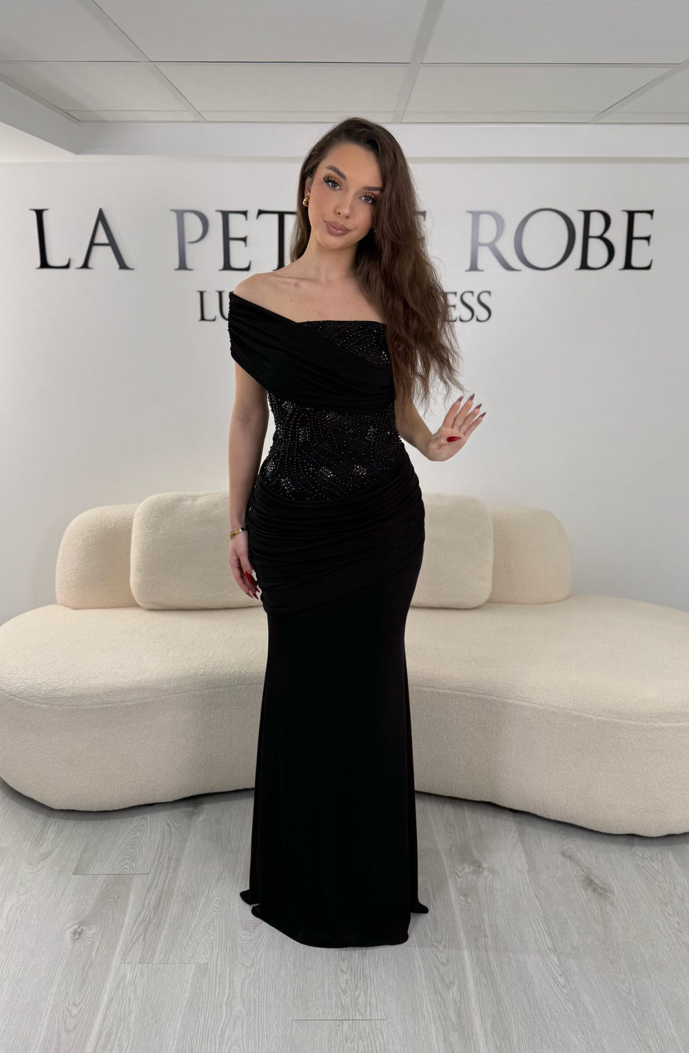 Robe de soirée noire en jersey stretch, sans manche avec col asymétrique. Coupe ajustée sans fente, idéale pour une allure élégante et moderne.
