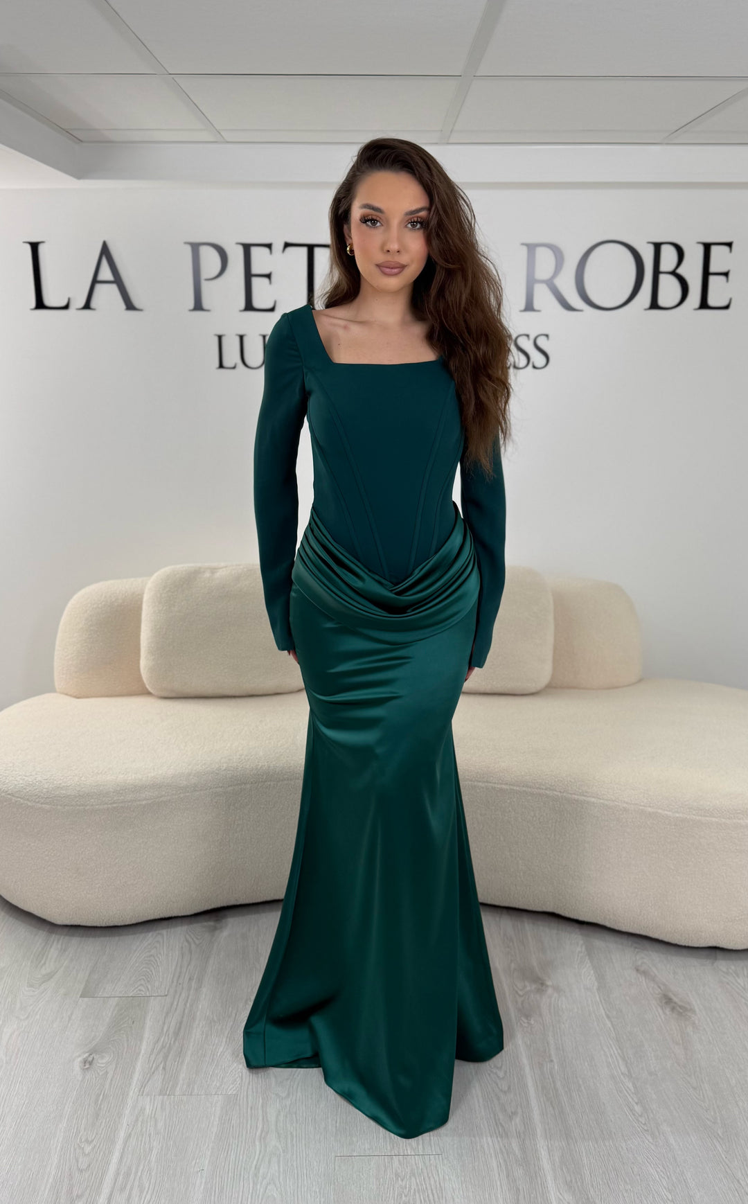 Robe de soirée vert émeraude avec col carré, manches longues et corset structuré. Coupe ajustée sans fente avec drapé élégant, idéale pour une allure chic.