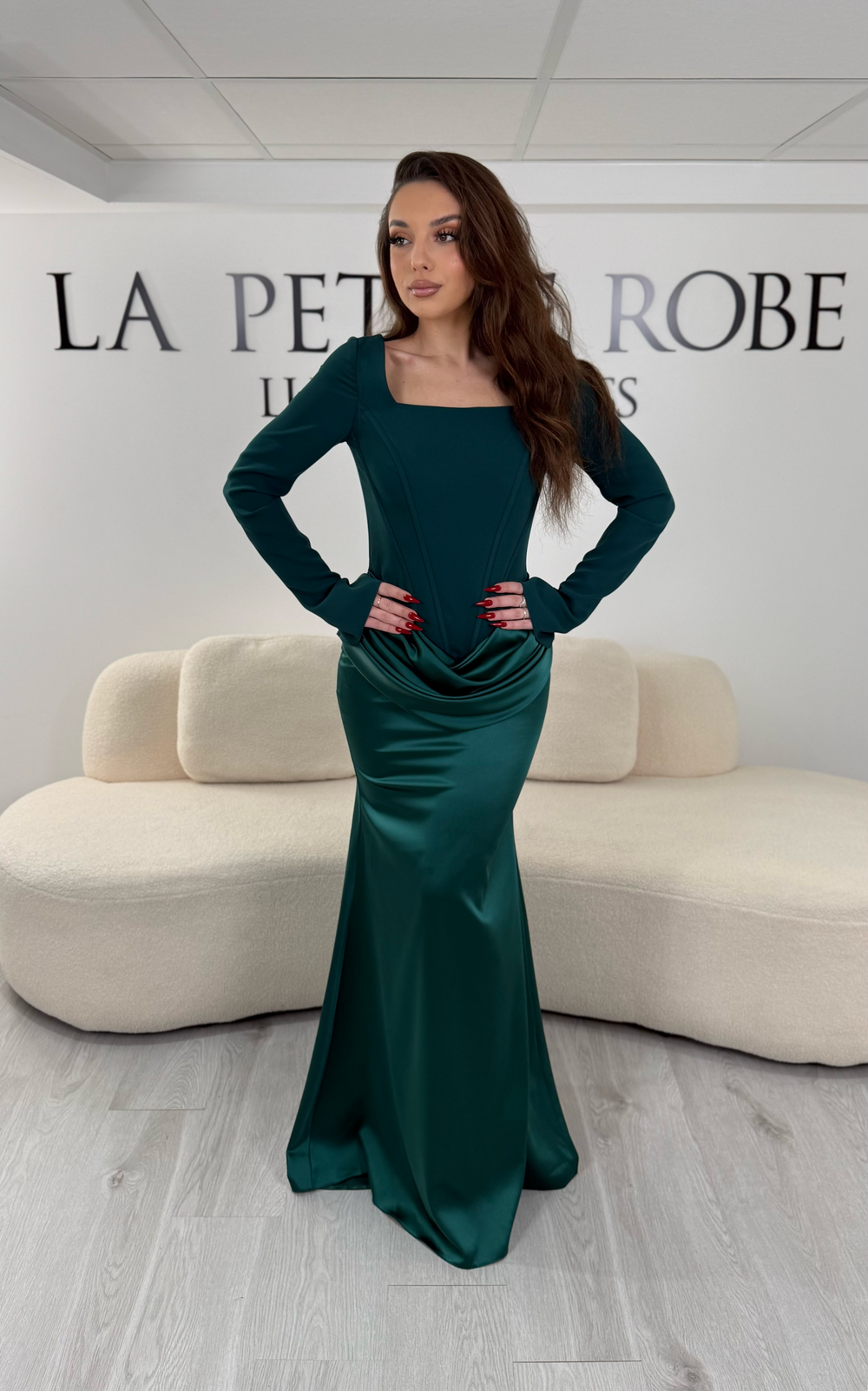 Robe de soirée vert émeraude avec col carré, manches longues et corset structuré. Coupe ajustée sans fente avec drapé élégant, idéale pour une allure chic.