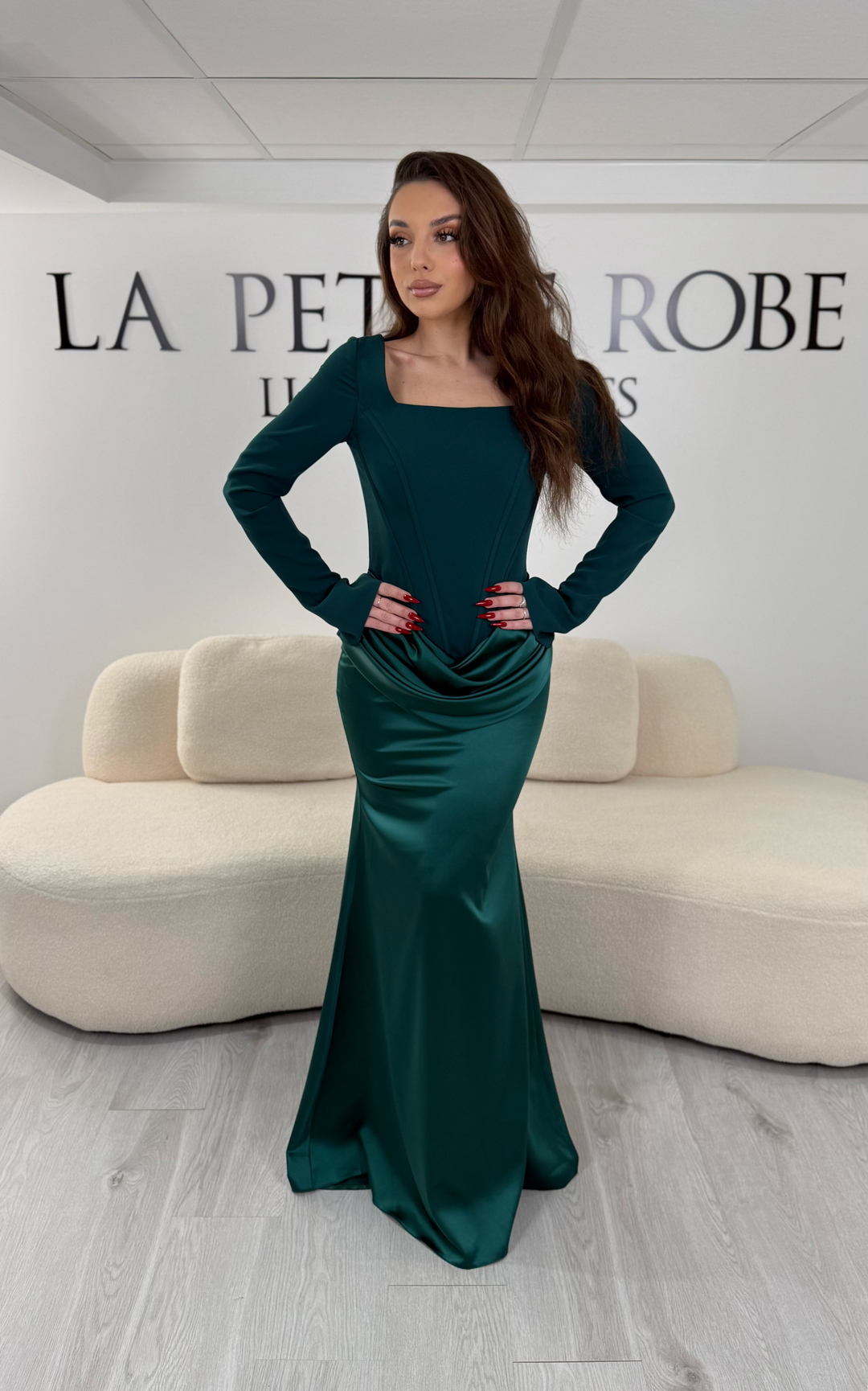 Robe de soirée vert émeraude avec col carré, manches longues et corset structuré. Coupe ajustée sans fente avec drapé élégant, idéale pour une allure chic.