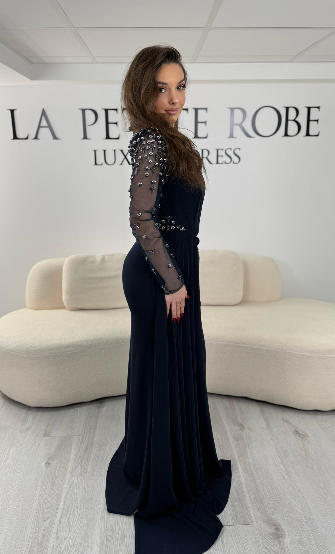 Robe de soirée bleu marine avec col rond et manches longues brodées. Coupe ajustée avec fente élégante, idéale pour une allure chic et raffinée.