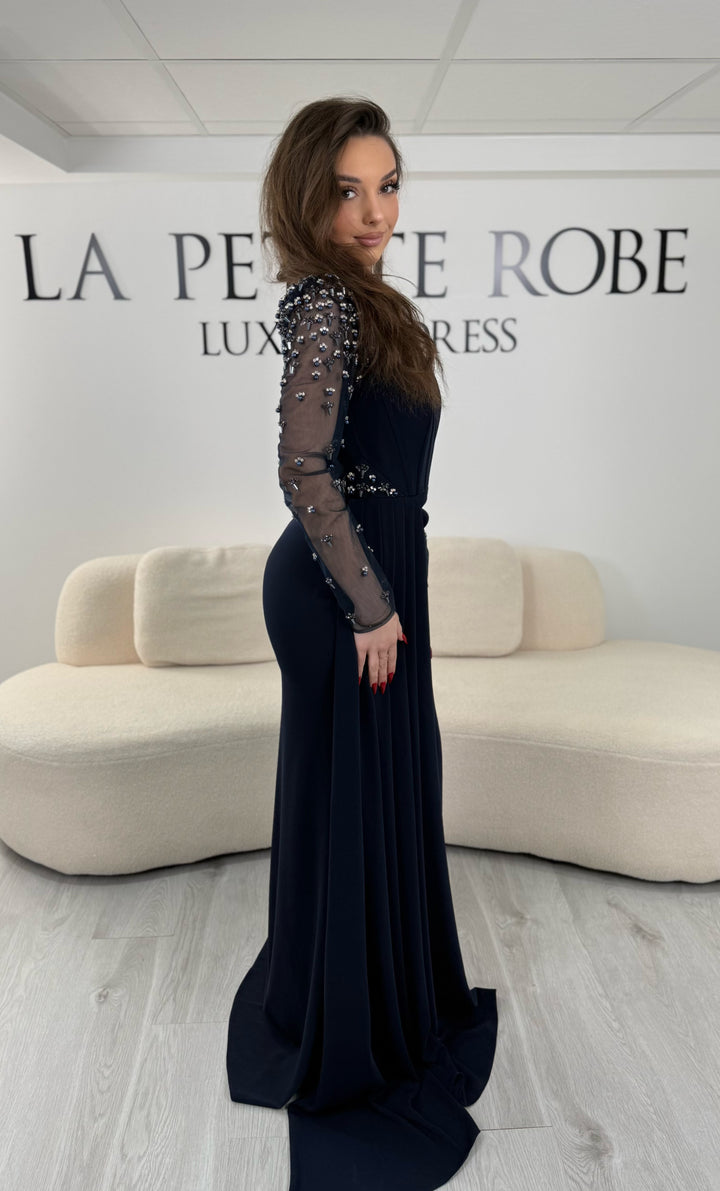 Robe de soirée bleu marine avec col rond et manches longues brodées. Coupe ajustée avec fente élégante, idéale pour une allure chic et raffinée.