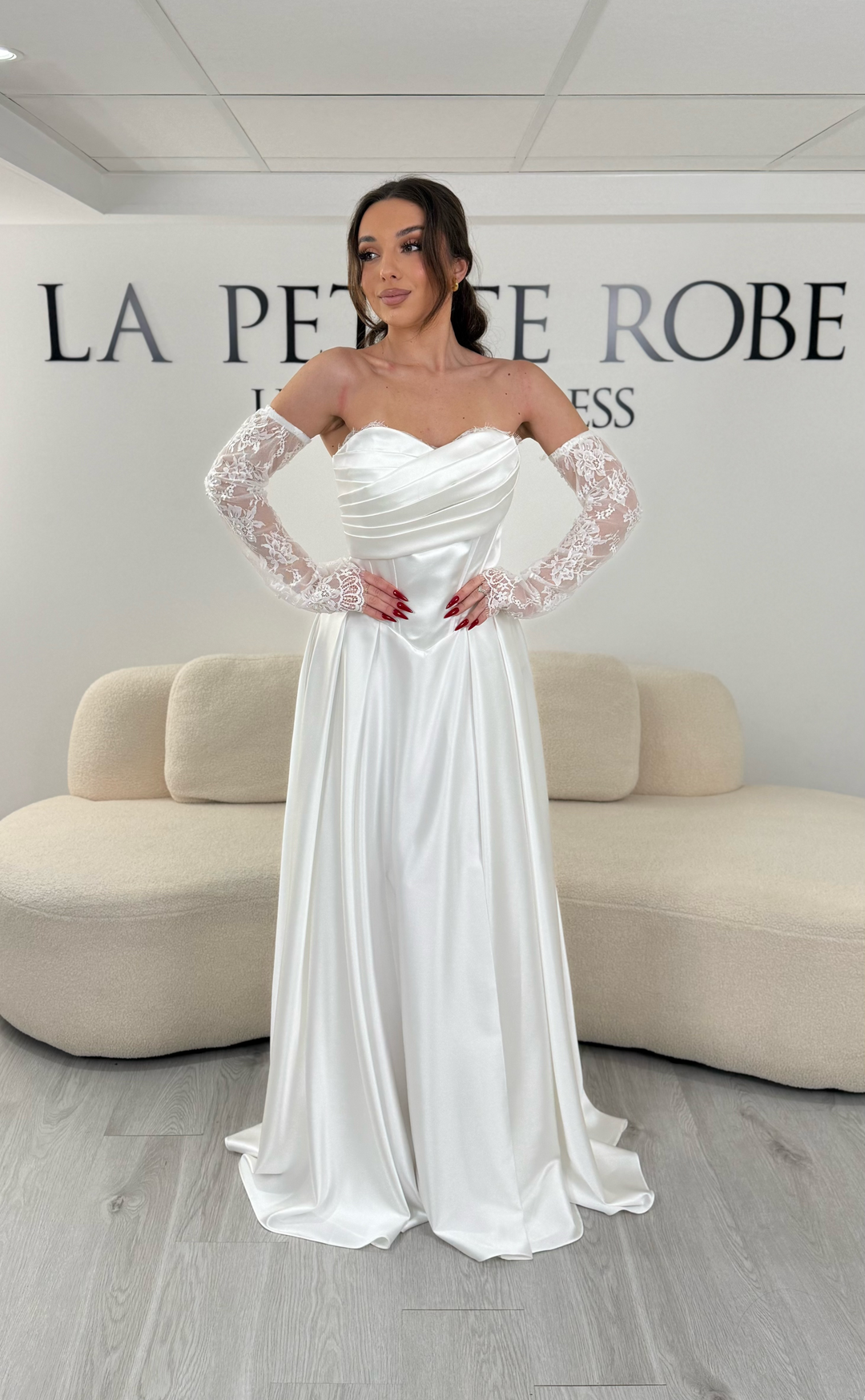 Robe de mariée blanche avec col bustier et manches amovibles en dentelle. Coupe fluide avec fente élégante, idéale pour une allure romantique et chic.