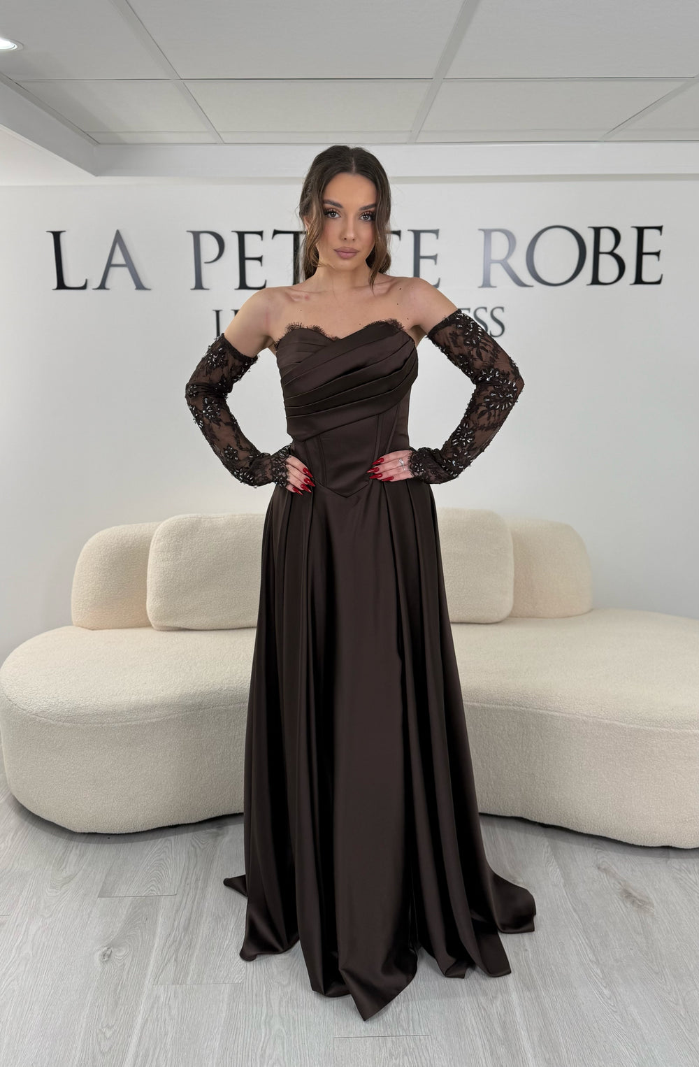 Robe de soirée marron avec col bustier et manches amovibles en dentelle. Coupe fluide avec fente élégante, idéale pour une allure chic et sophistiquée.