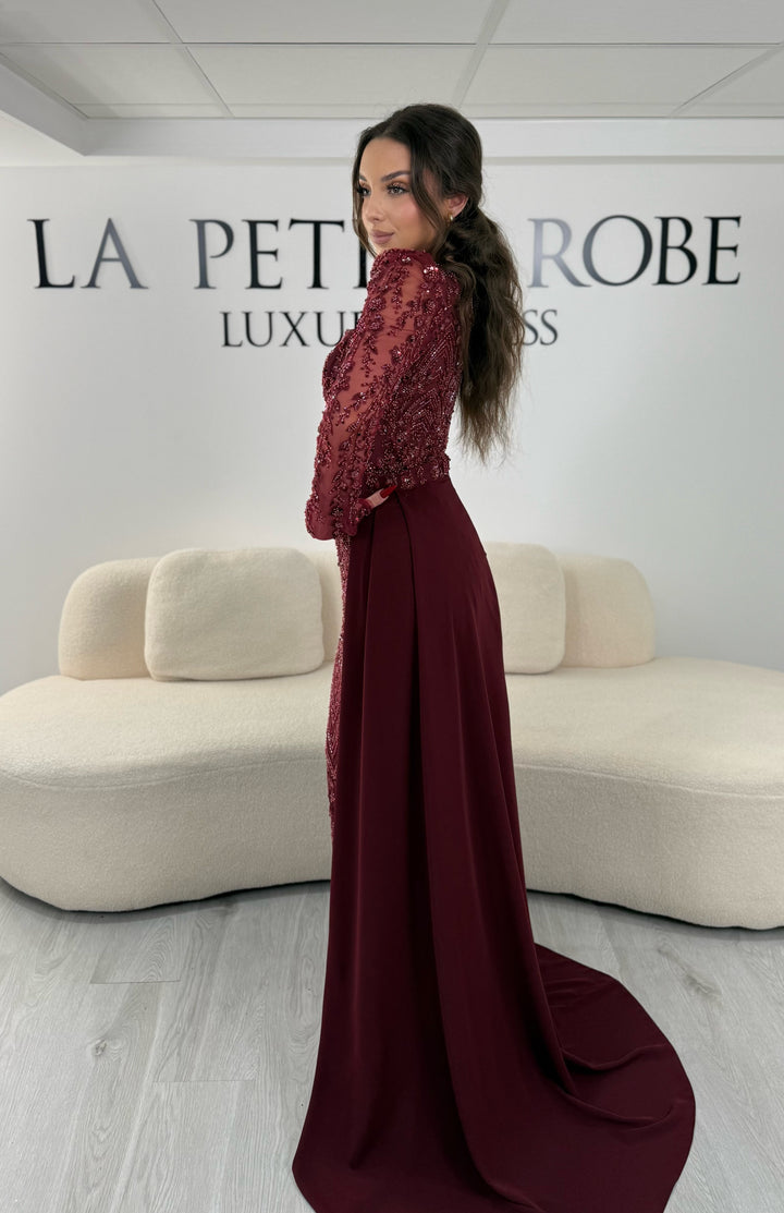 Robe de soirée bordeaux avec col carré et manches longues brodées. Coupe ajustée sans fente avec traîne amovible, idéale pour une allure élégante.