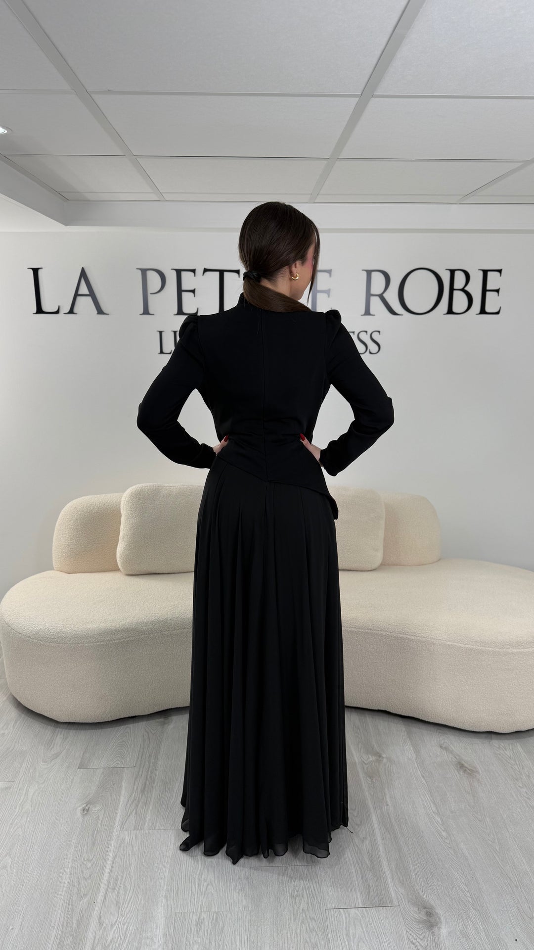 Robe de soirée noire avec manches longues et col montant. Coupe fluide sans fente, idéale pour une allure élégante et sophistiquée.