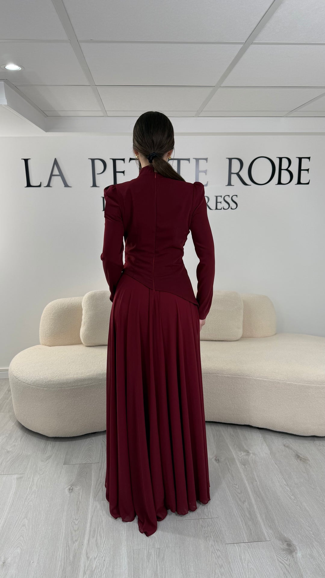 Robe de soirée bordeaux avec manches longues et col montant. Coupe fluide sans fente, idéale pour une allure élégante et sophistiquée.