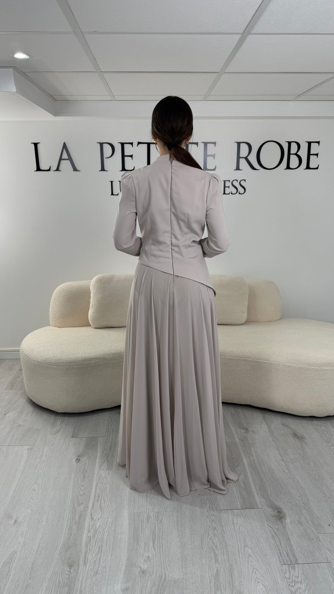 Robe de soirée beige avec manches longues et col montant. Coupe fluide sans fente, idéale pour une allure élégante et sophistiquée.