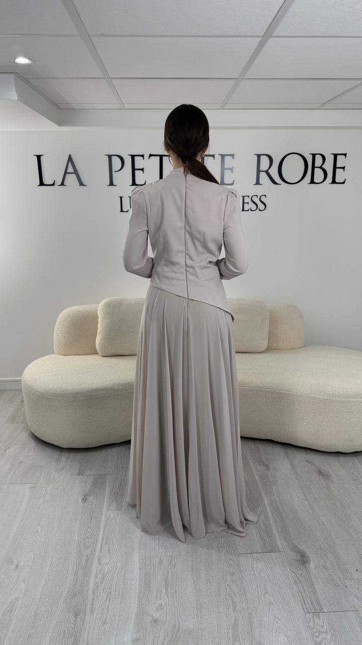Robe de soirée beige avec manches longues et col montant. Coupe fluide sans fente, idéale pour une allure élégante et sophistiquée.