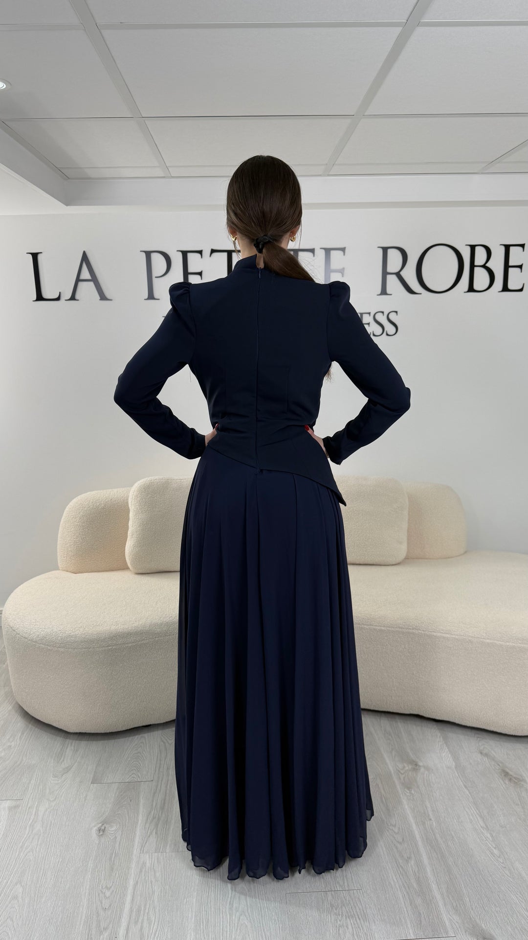 Robe de soirée bleu marine avec manches longues et col montant. Coupe fluide sans fente, idéale pour une allure élégante et sophistiquée.