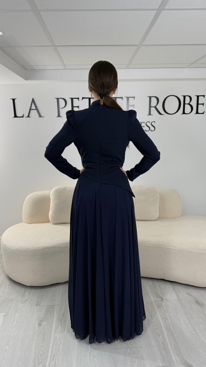 Robe de soirée bleu marine avec manches longues et col montant. Coupe fluide sans fente, idéale pour une allure élégante et sophistiquée.