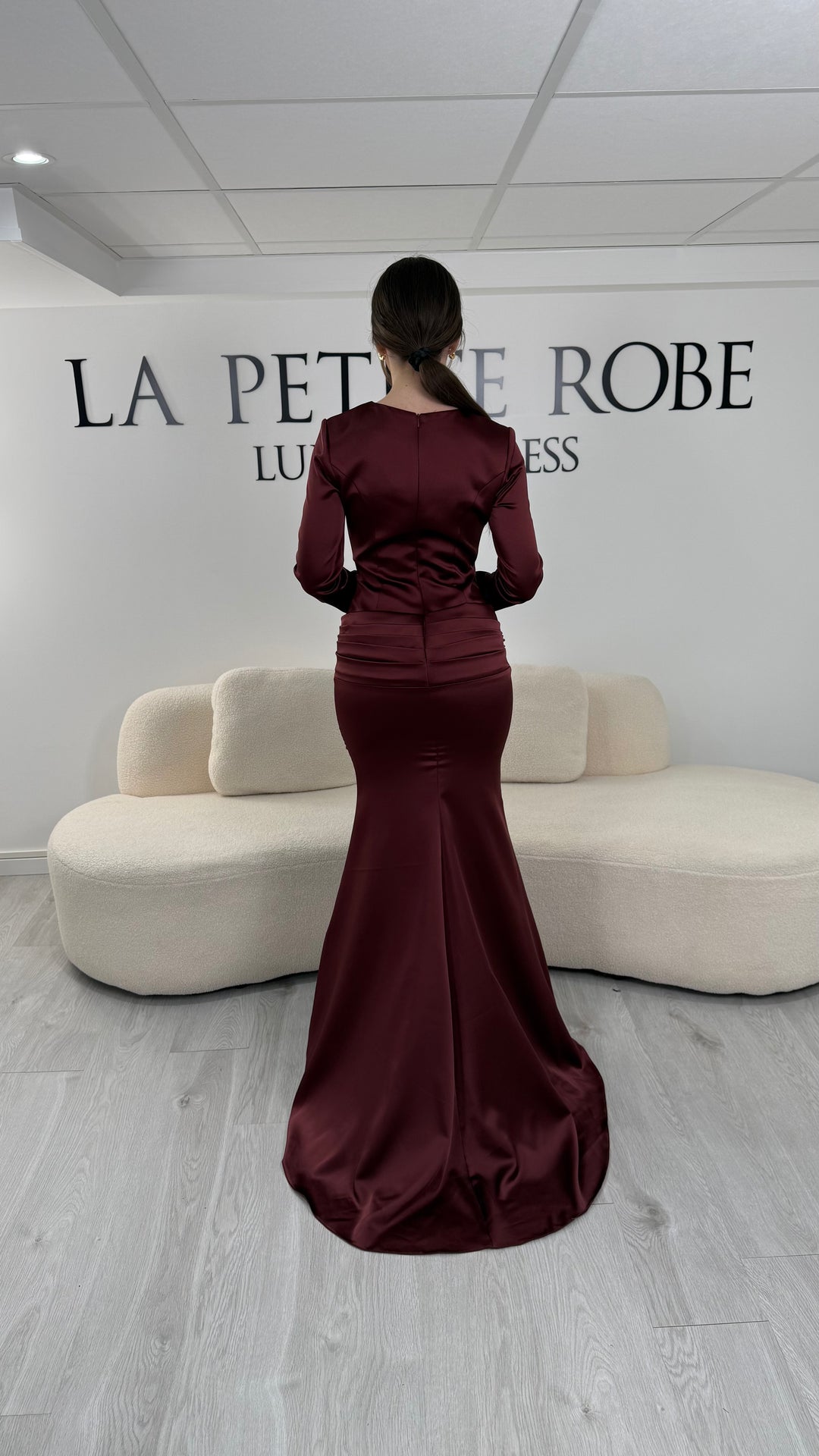 Robe de soirée bordeaux avec manches longues et coupe ajustée. Sans fente, tissu satiné et détails élégants pour une allure sophistiquée.