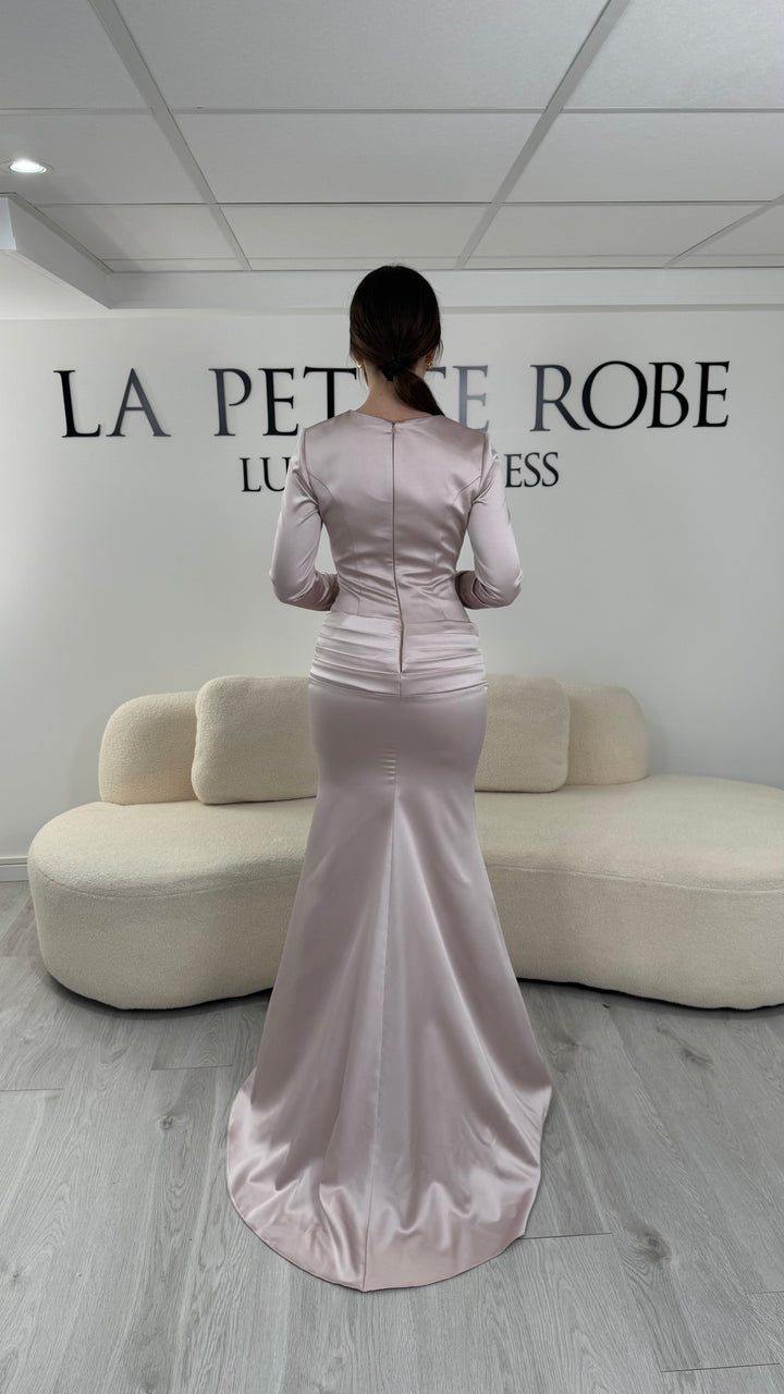 Robe de soirée rose avec manches longues et coupe ajustée. Sans fente, tissu satiné et détails élégants pour une allure sophistiquée.