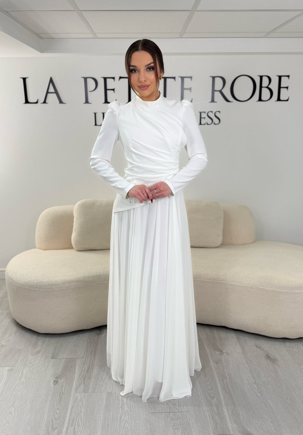 Robe de mariée modeste blanche avec manches longues et col montant. Coupe fluide sans fente, idéale pour une allure élégante et raffinée.