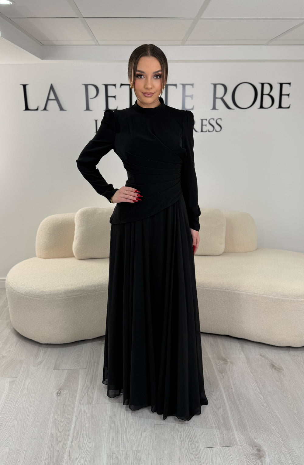 Robe de soirée noire avec manches longues et col montant. Coupe fluide sans fente, idéale pour une allure élégante et sophistiquée.