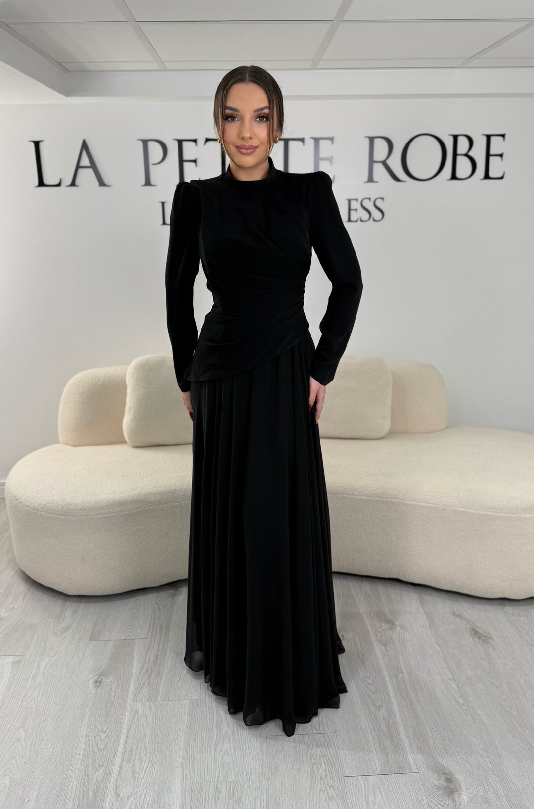 Robe de soirée noire avec manches longues et col montant. Coupe fluide sans fente, idéale pour une allure élégante et sophistiquée.