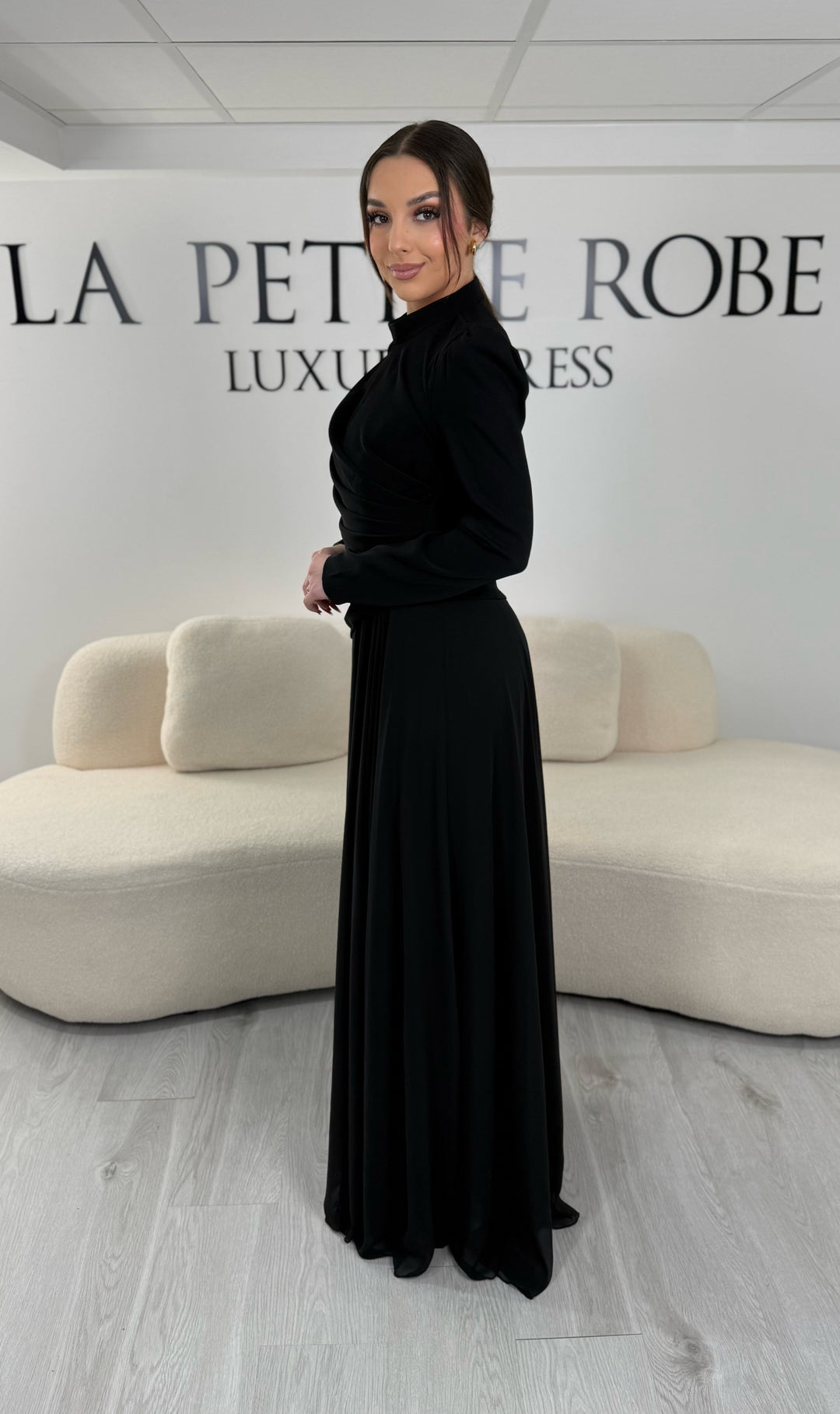 Robe de soirée noire avec manches longues et col montant. Coupe fluide sans fente, idéale pour une allure élégante et sophistiquée.