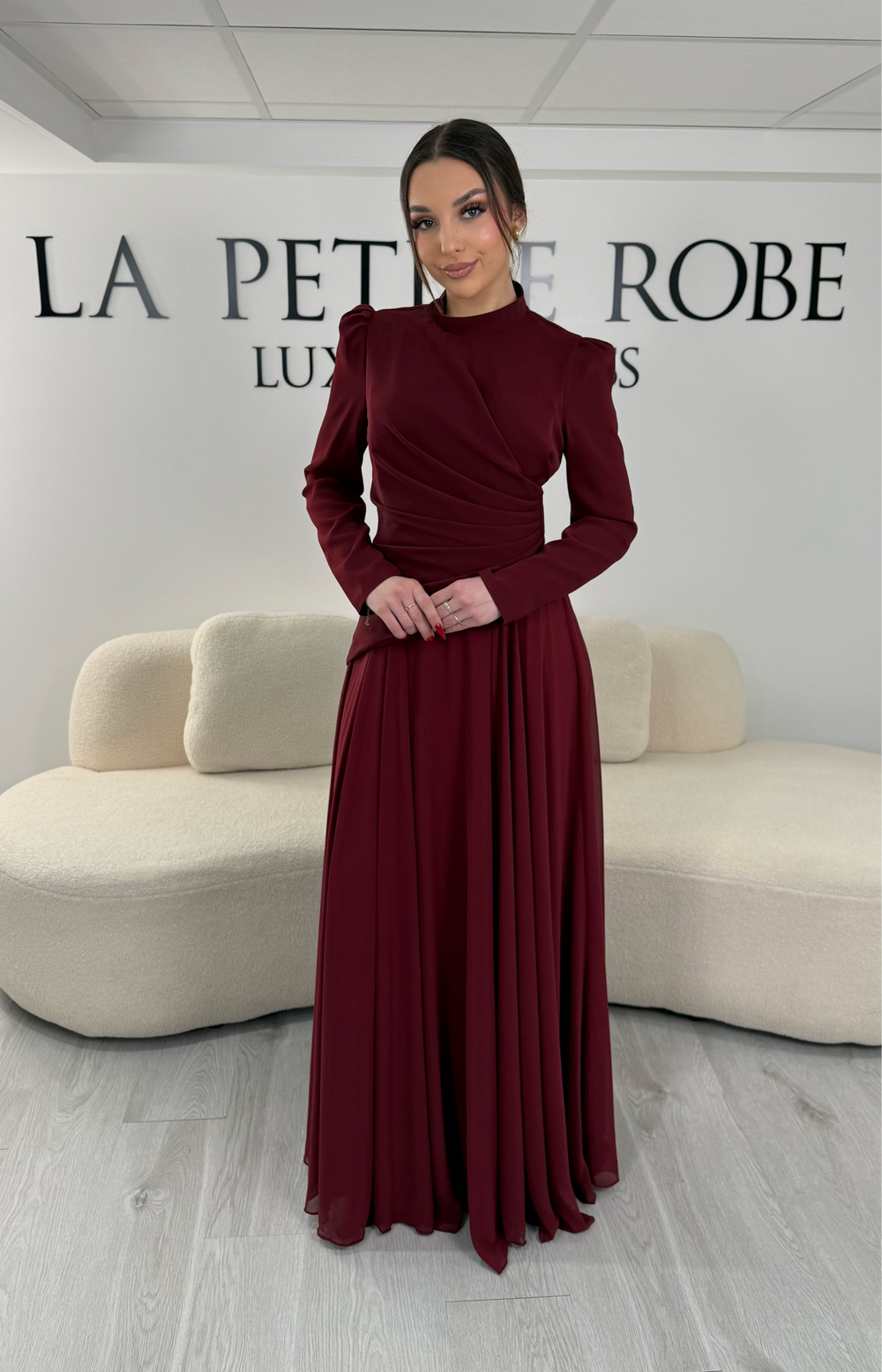 Robe de soirée bordeaux avec manches longues et col montant. Coupe fluide sans fente, idéale pour une allure élégante et sophistiquée.