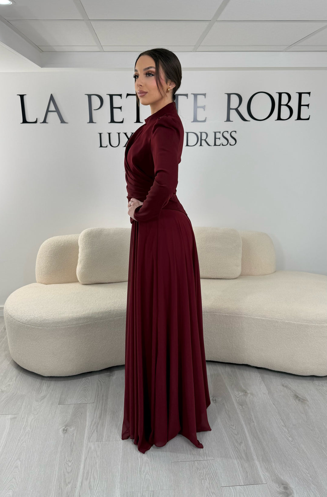 Robe de soirée bordeaux avec manches longues et col montant. Coupe fluide sans fente, idéale pour une allure élégante et sophistiquée.