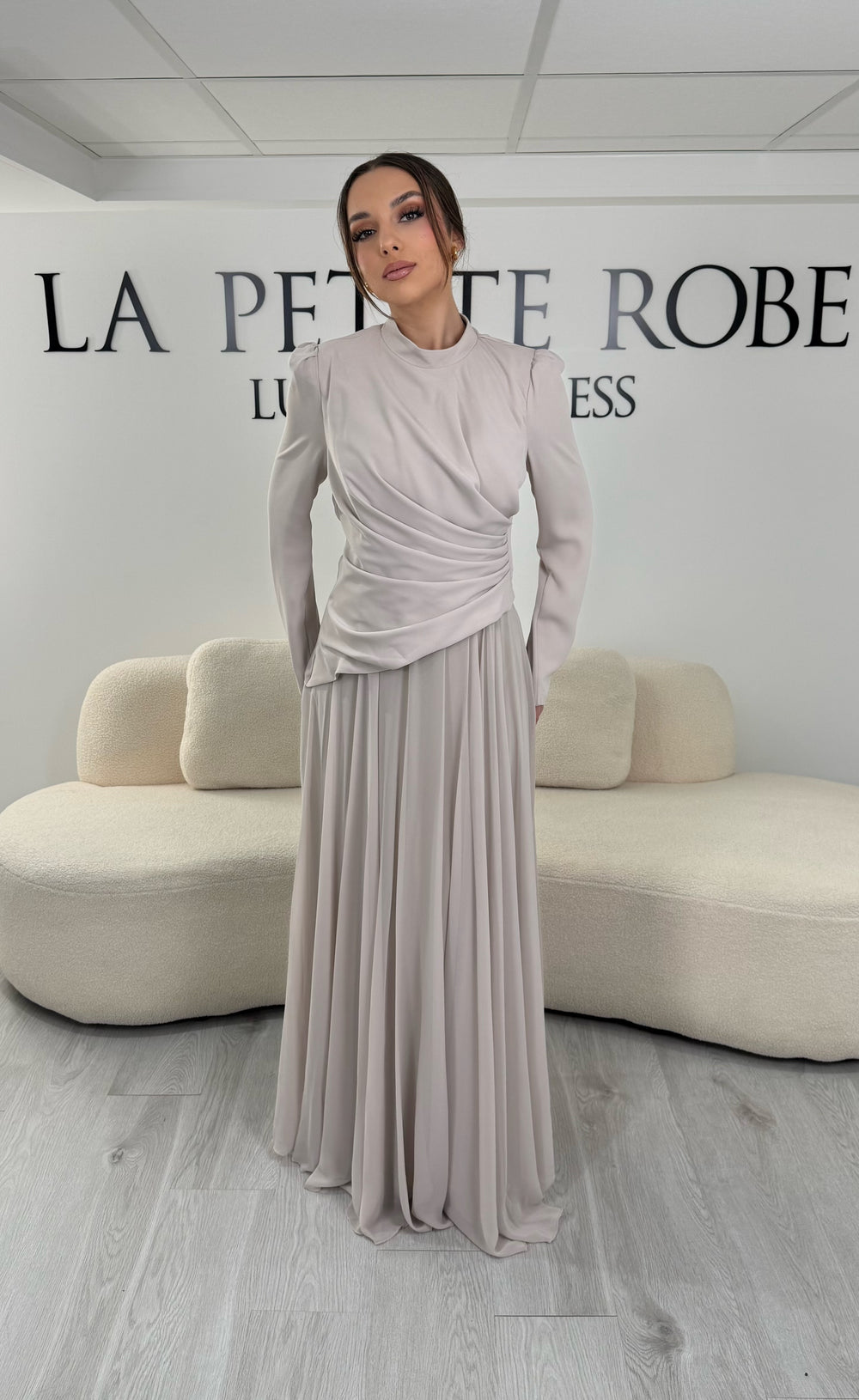 Robe de soirée beige avec manches longues et col montant. Coupe fluide sans fente, idéale pour une allure élégante et sophistiquée.