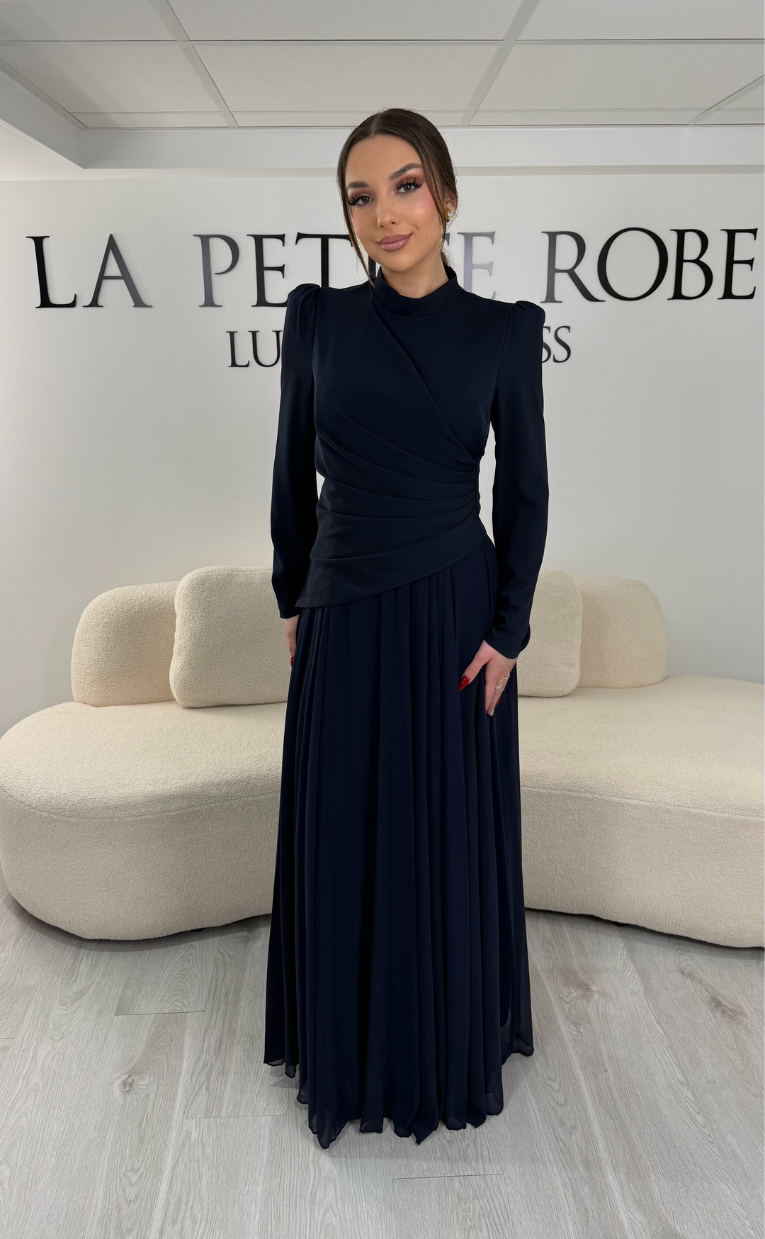 Robe de soirée bleu marine avec manches longues et col montant. Coupe fluide sans fente, idéale pour une allure élégante et sophistiquée.