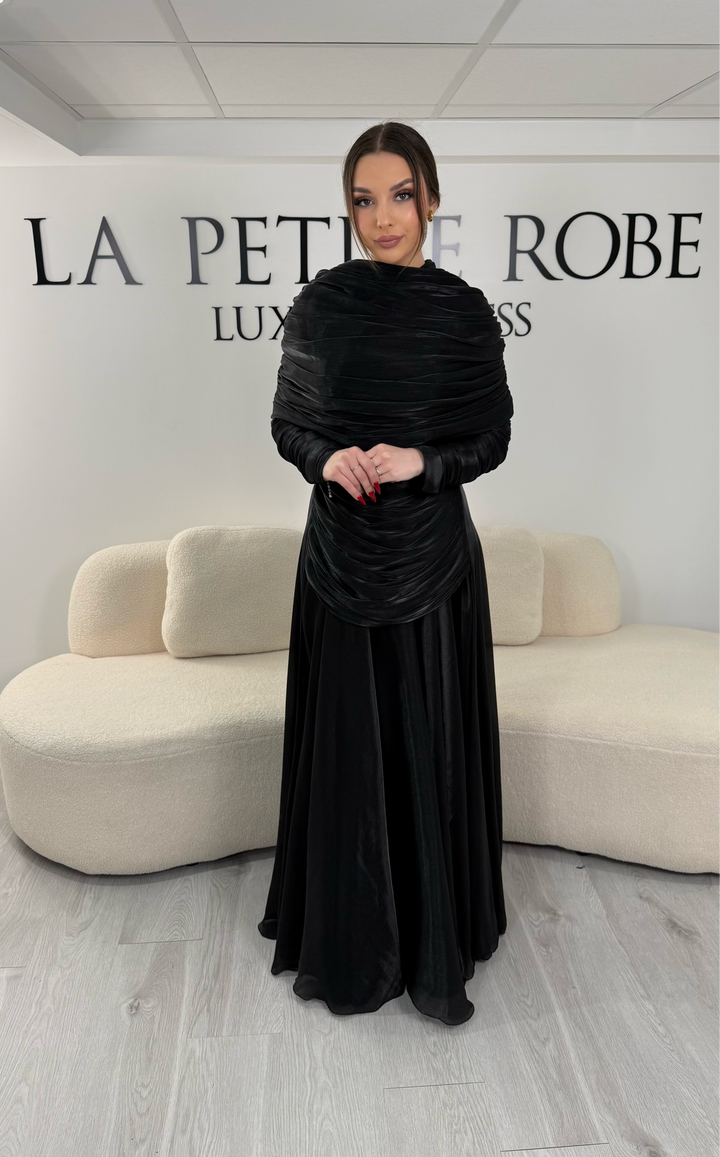 Robe de soirée modeste noire avec manches longues et drapé élégant. Coupe fluide sans fente, idéale pour une allure chic et raffinée.