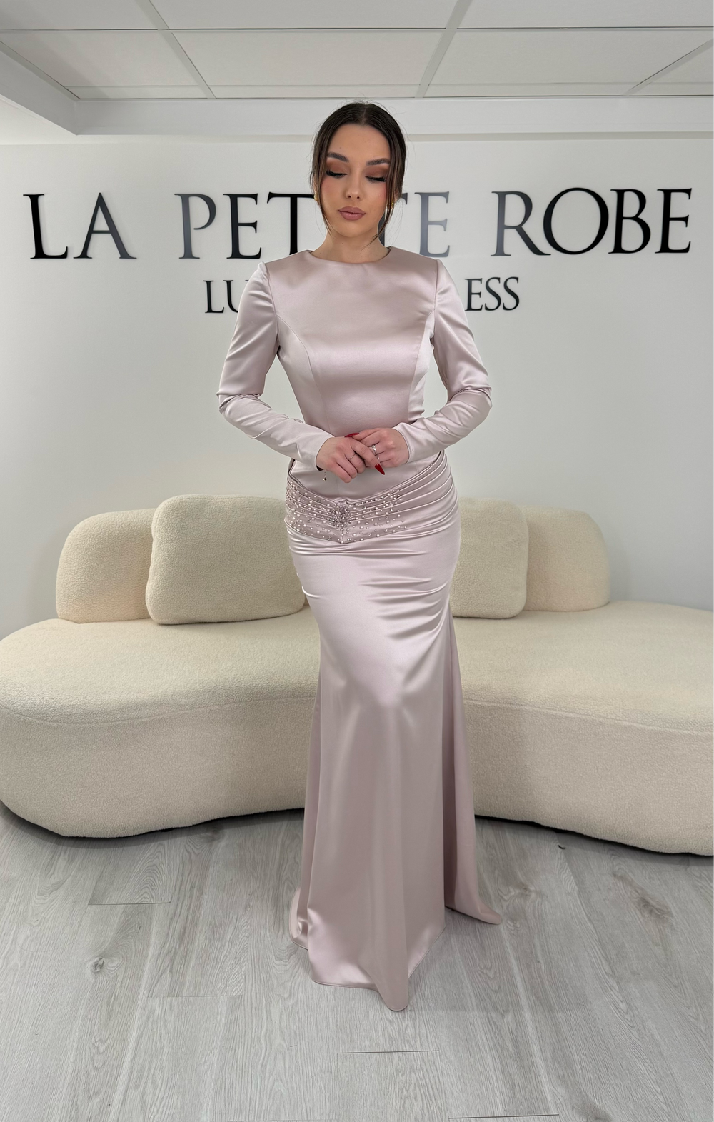 Robe de soirée rose avec manches longues et coupe ajustée. Sans fente, tissu satiné et détails élégants pour une allure sophistiquée.