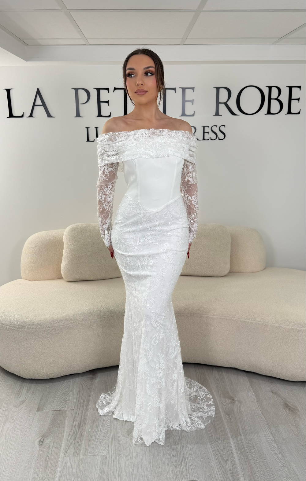 Robe de mariée blanche à col bateau avec manches longues en dentelle. Coupe sirène élégante, sans fente, pour une allure chic et raffinée.