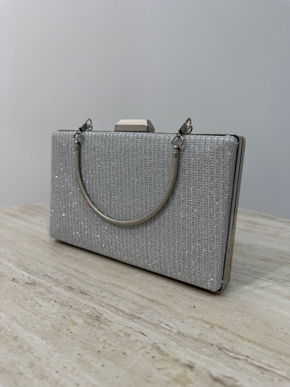 Pochette de soirée argentée pailletée élégante avec anse main et bandoulière chaîne. Idéale pour mariage, cérémonie et soirée chic.