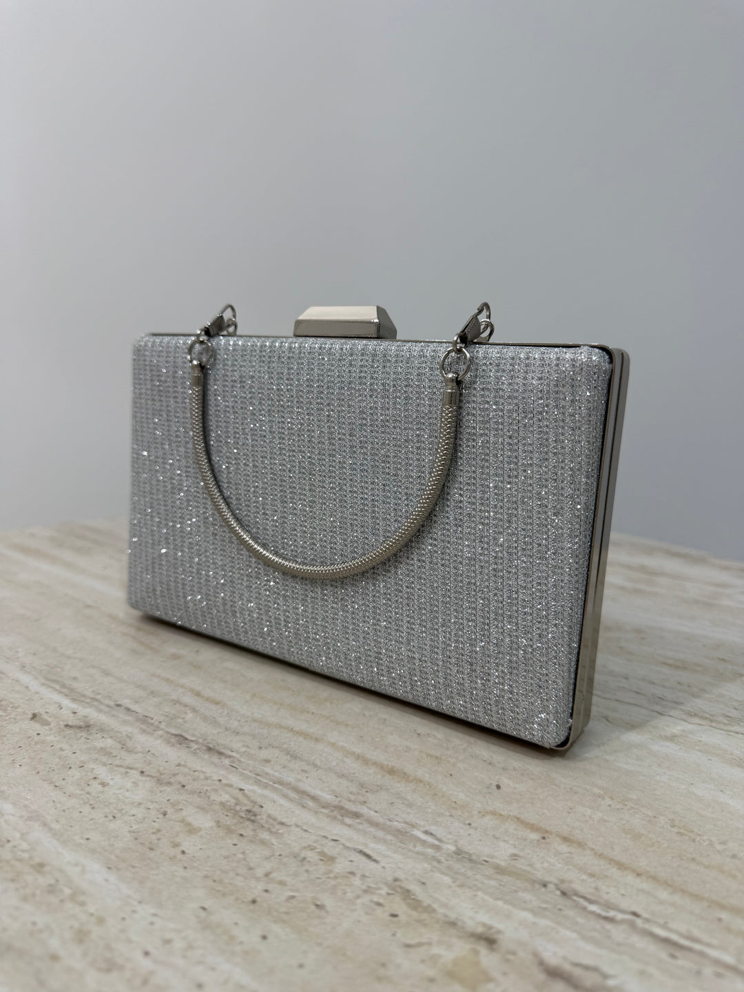 Pochette de soirée argentée pailletée élégante avec anse main et bandoulière chaîne. Idéale pour mariage, cérémonie et soirée chic.