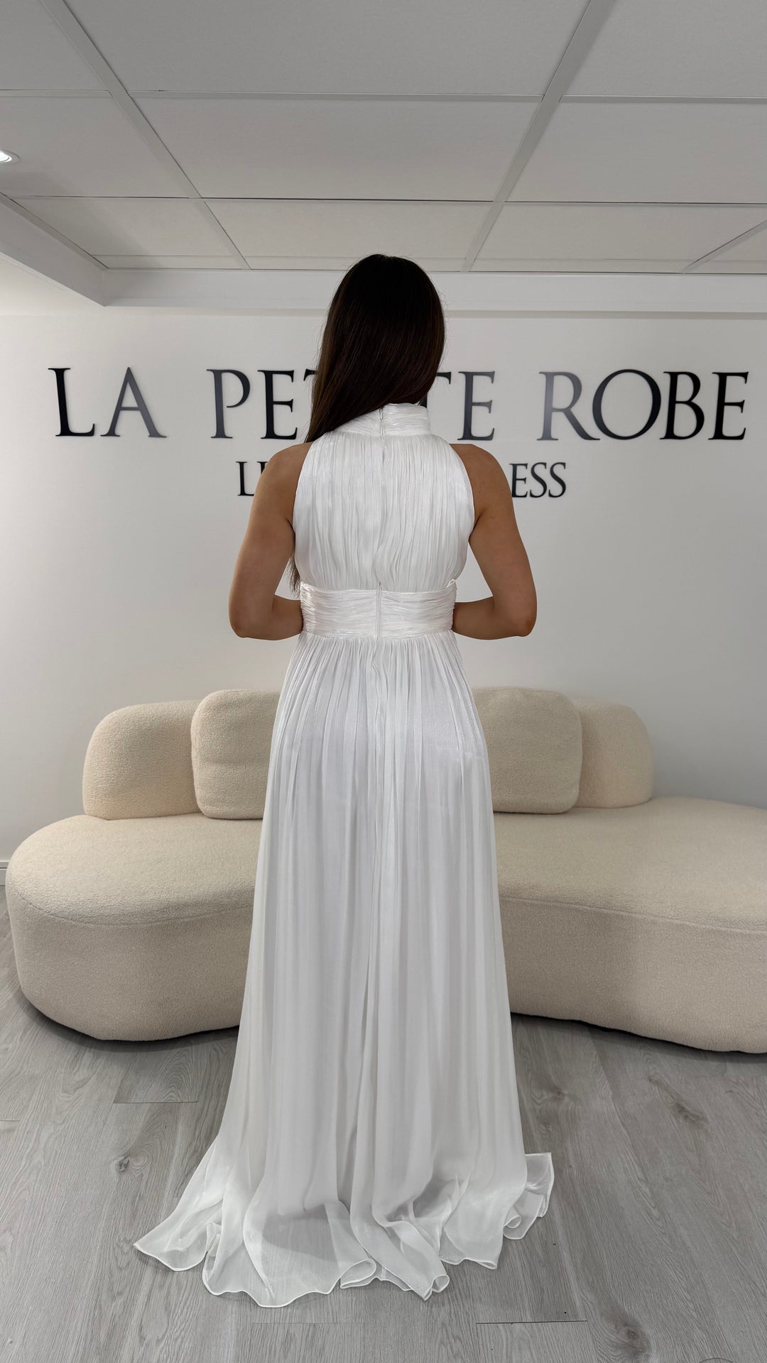 Robe de mariée blanche longue plissée avec col montant et coupe sans manches. Une robe élégante sans fente idéale pour mariage civil, cérémonie et réception chic.