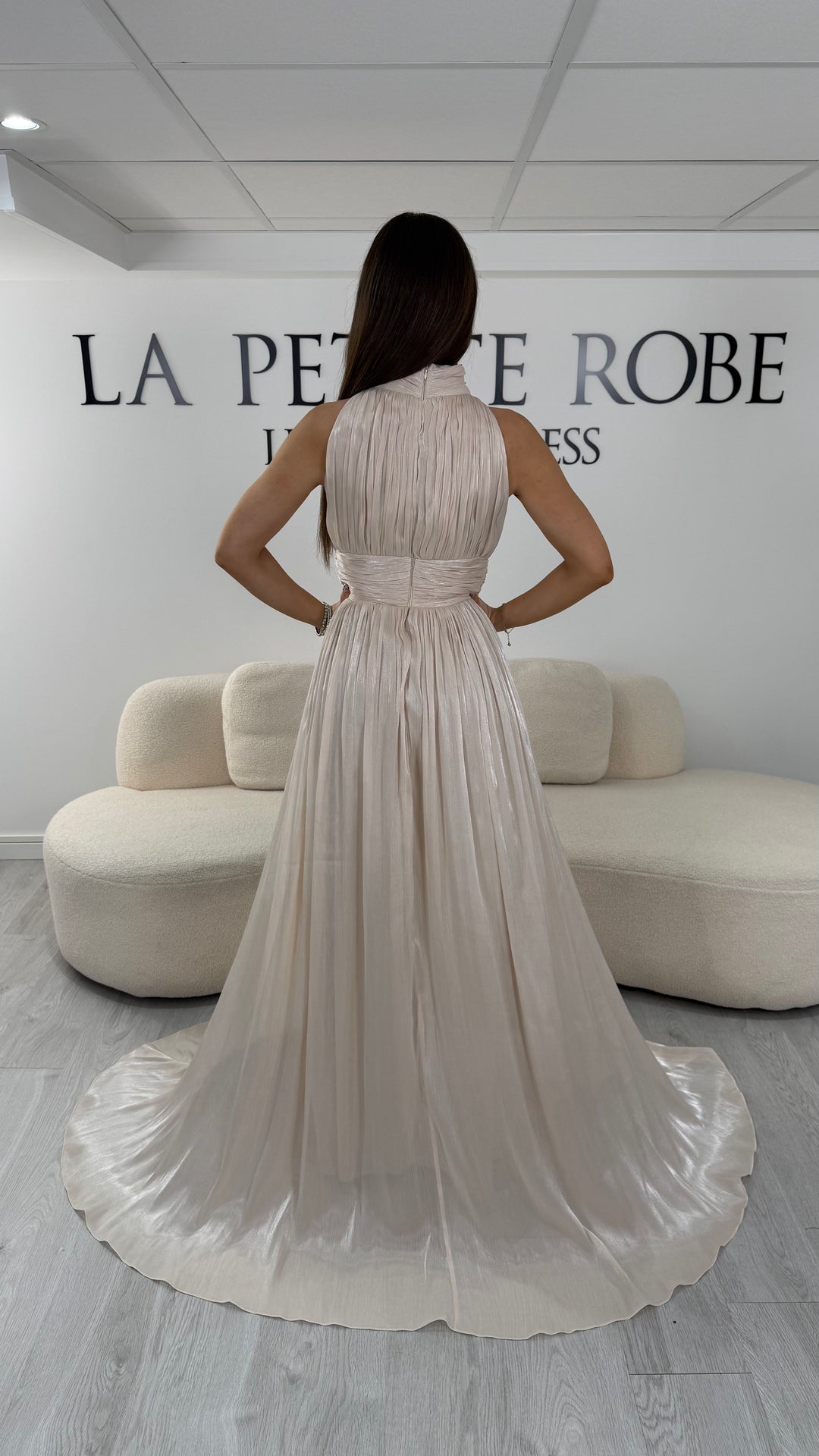 Robe de soirée beige longue plissée avec col montant et coupe sans manches. Une robe élégante sans fente idéale pour mariage, cérémonie et soirée chic.