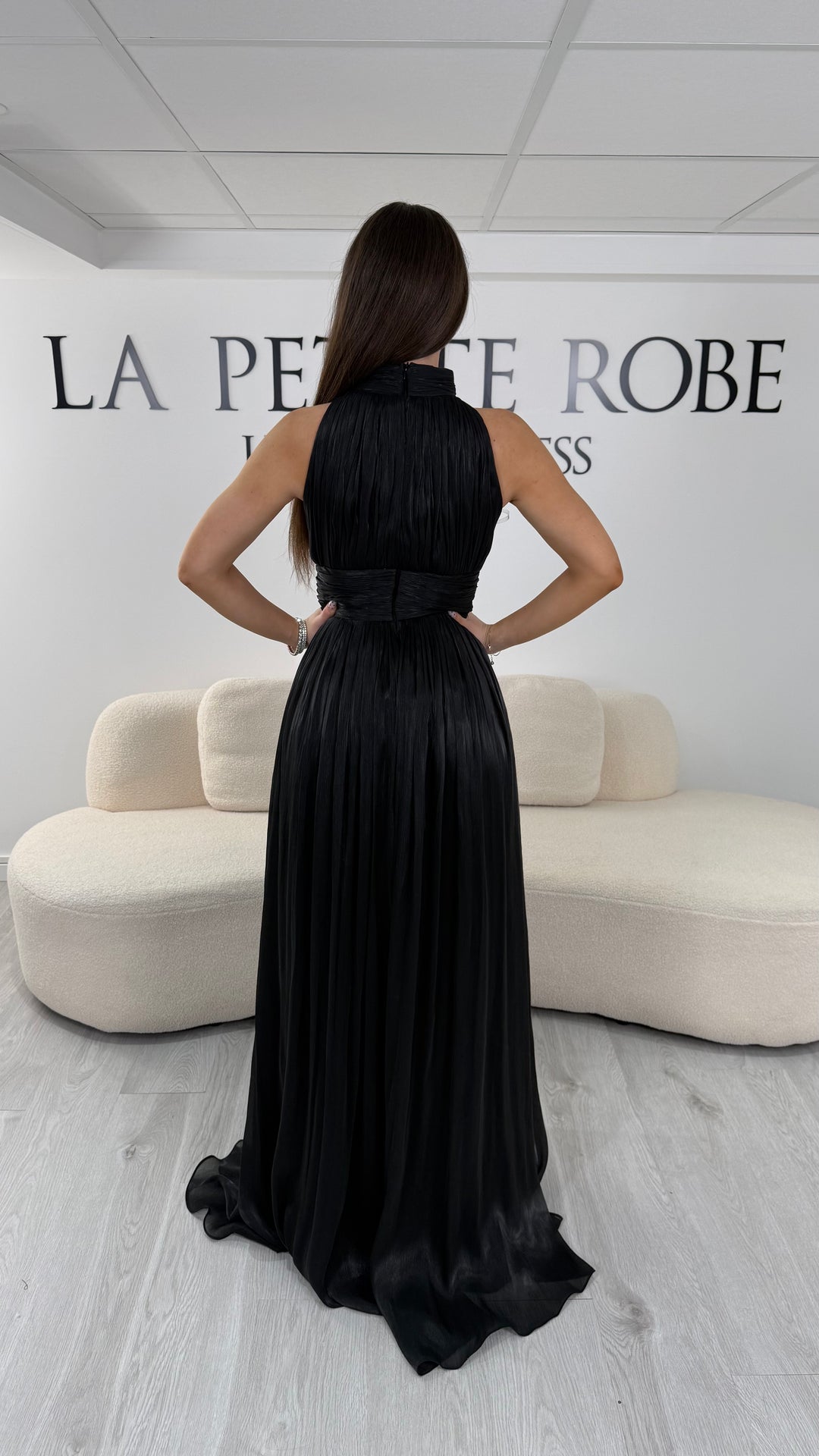Robe de soirée noire longue plissée avec col montant et coupe sans manches. Une robe élégante sans fente idéale pour mariage, cérémonie et soirée chic.